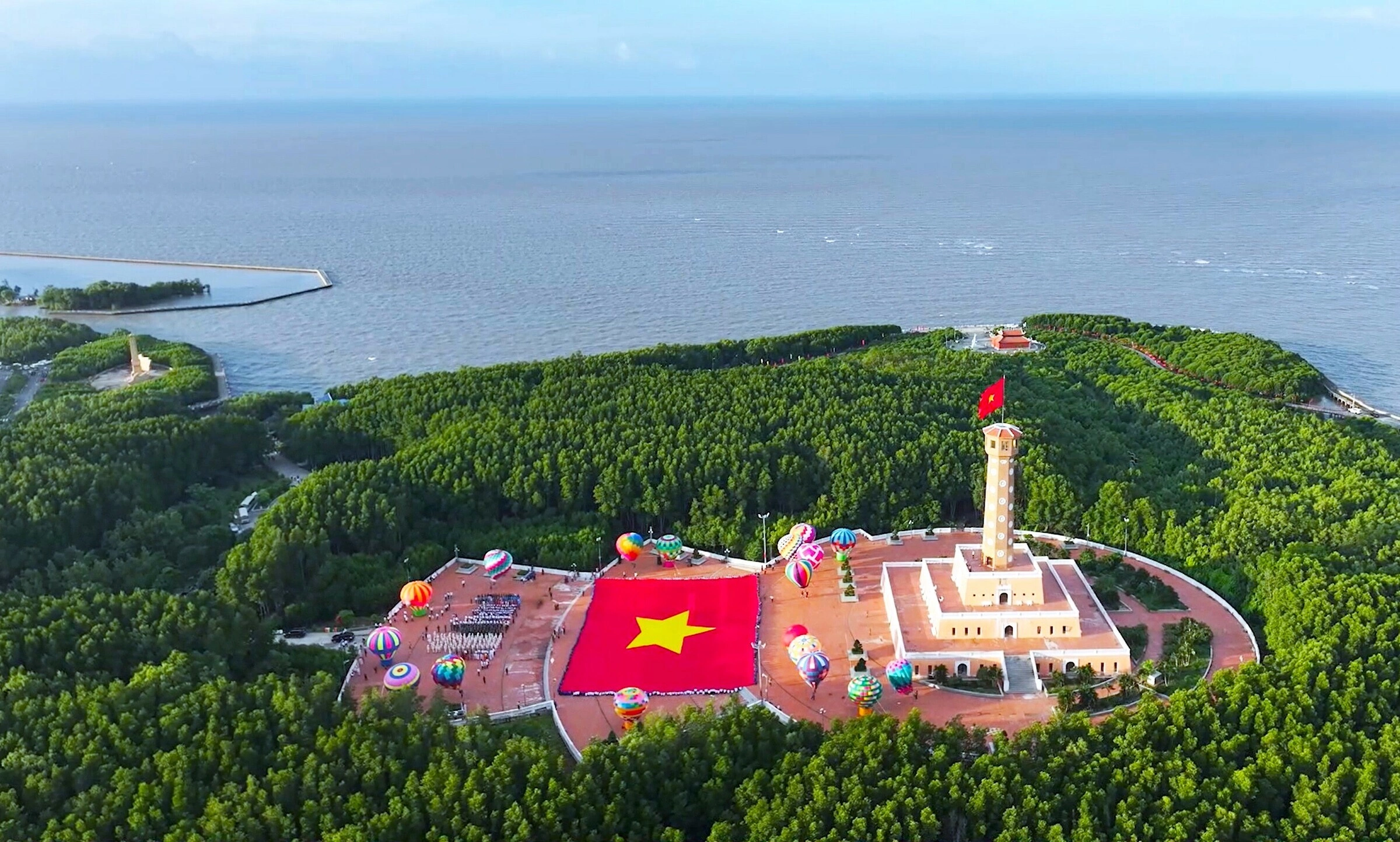 Lá cờ Tổ quốc tung bay trên Cột Cờ Hà Nội tại Mũi Cà Mau dưới trời mùa khô nắng vàng rực rỡ
