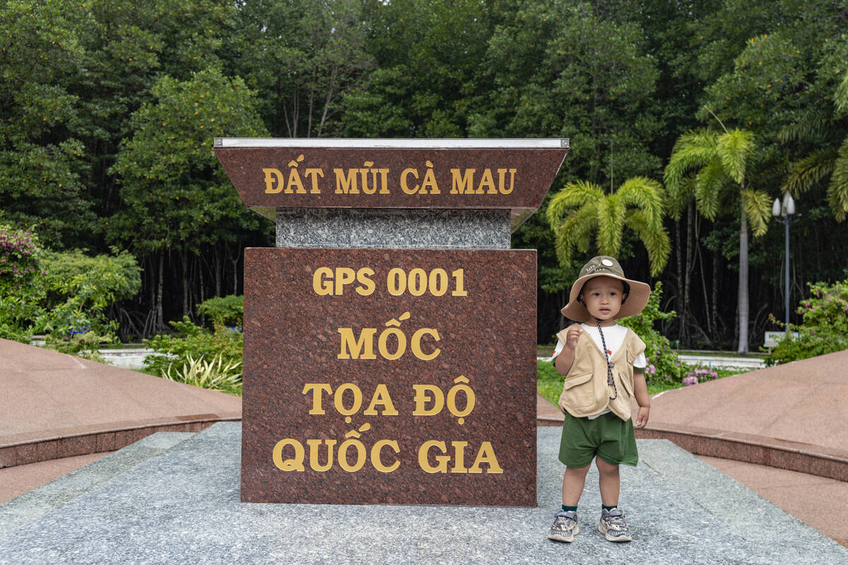 Bé nhỏ đứng trước mốc tọa độ GPS 0001 Đất Mũi Cà Mau