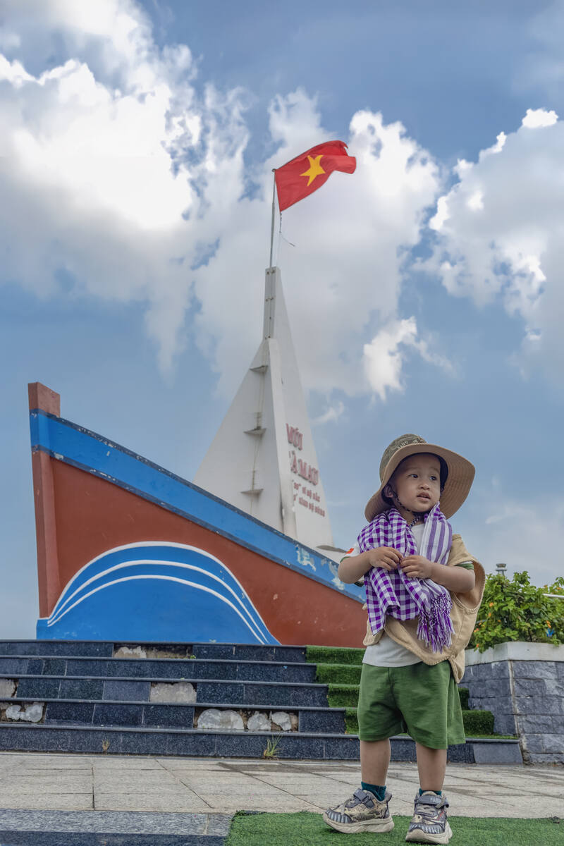 Bé nhỏ chụp ảnh trước tượng đài thuyền buồm Mũi Cà Mau