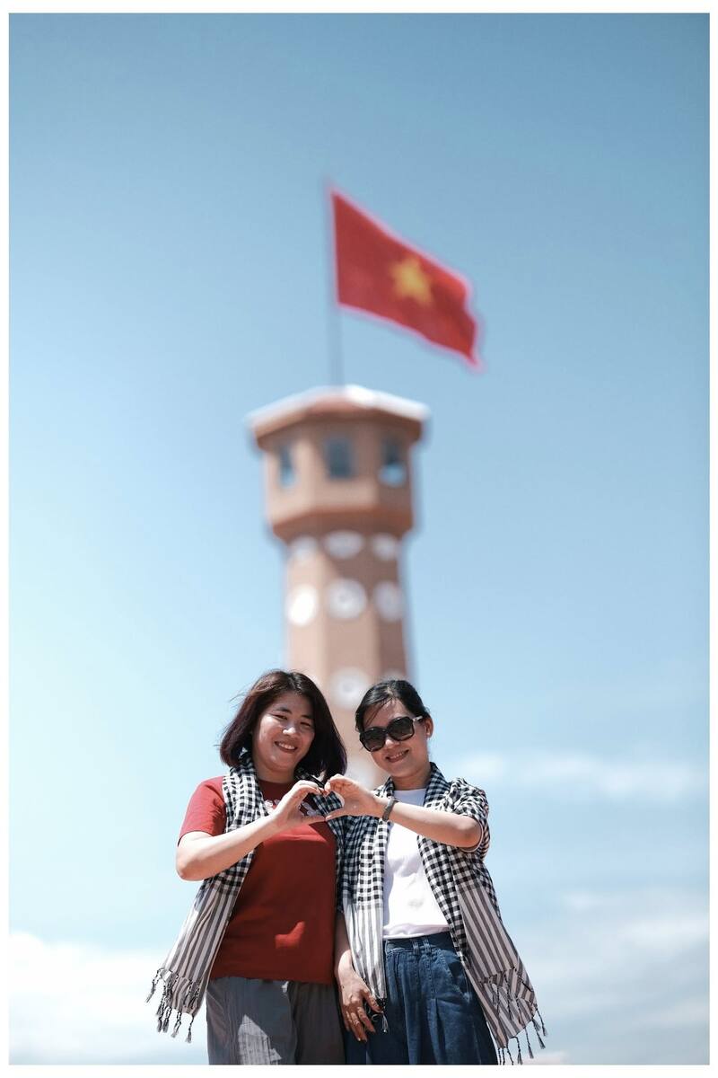 Hai du khách check-in trước cột cờ Hà Nội tại Đất Mũi