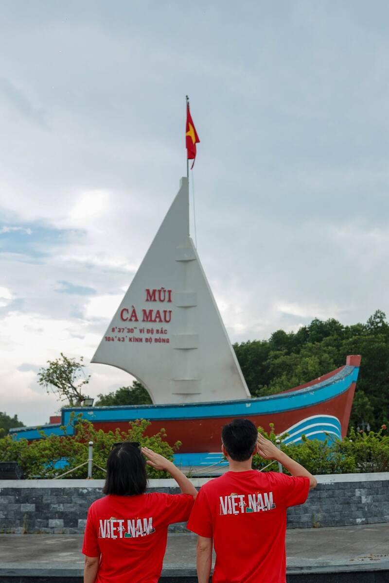 Cặp đôi chào cờ hướng về biểu tượng cánh buồm Đất Mũi