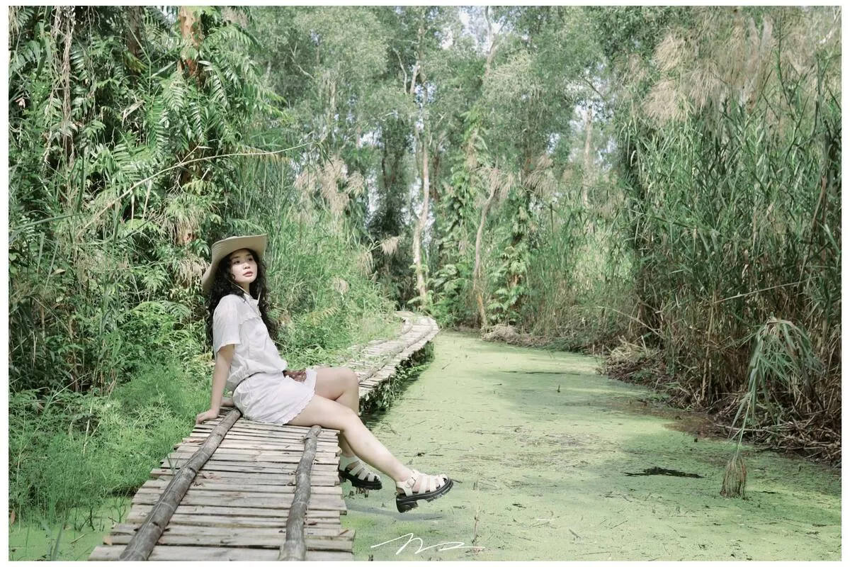 Young woman posing on the bamboo bridge through U Minh Ha cajuput forest